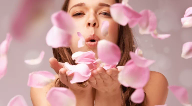 kobieta dmuchająca na płatki kwiatów